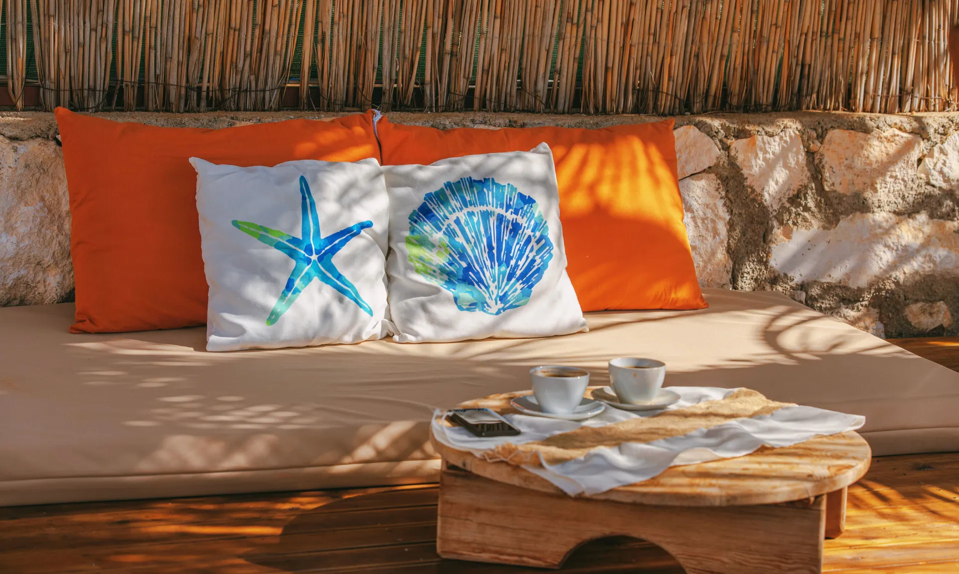 Cozy outdoor daybed with colorful accent pillows, a wooden coffee table, and a relaxing patio seating area.