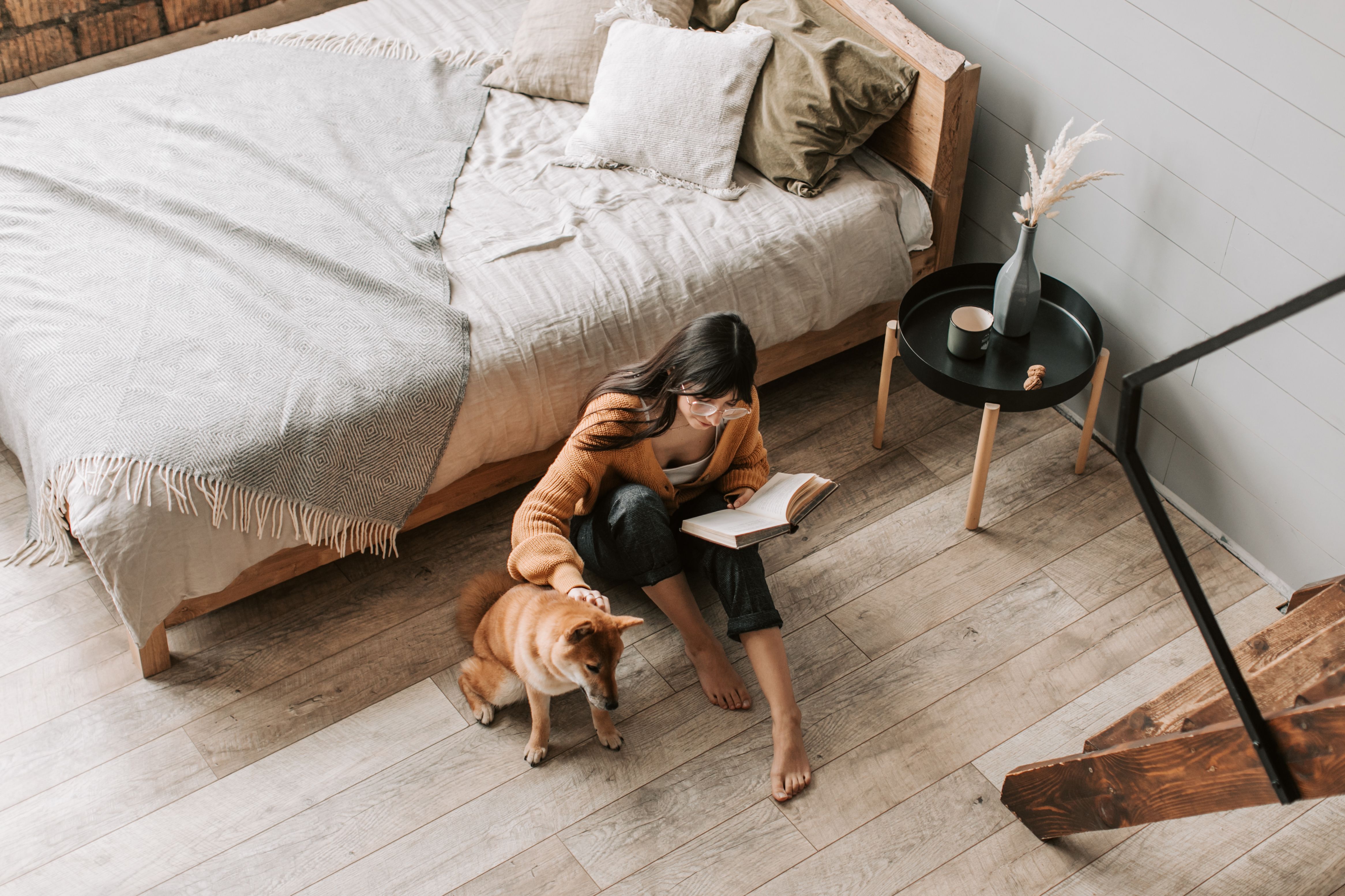 a girl sitting on her bedroom floor with her dog and a book