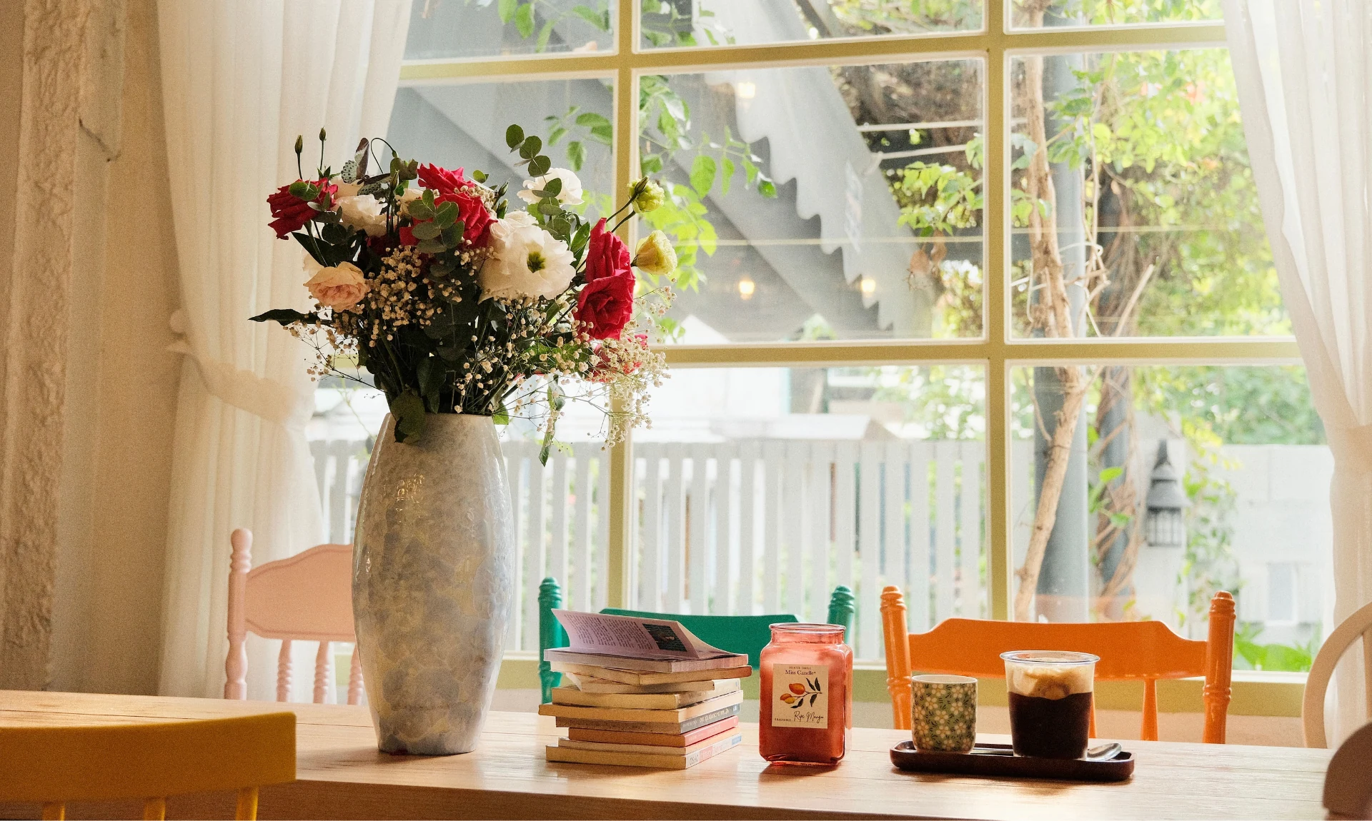 A fower vase, stack of books, and some thrifted home decor pieces set on a table
