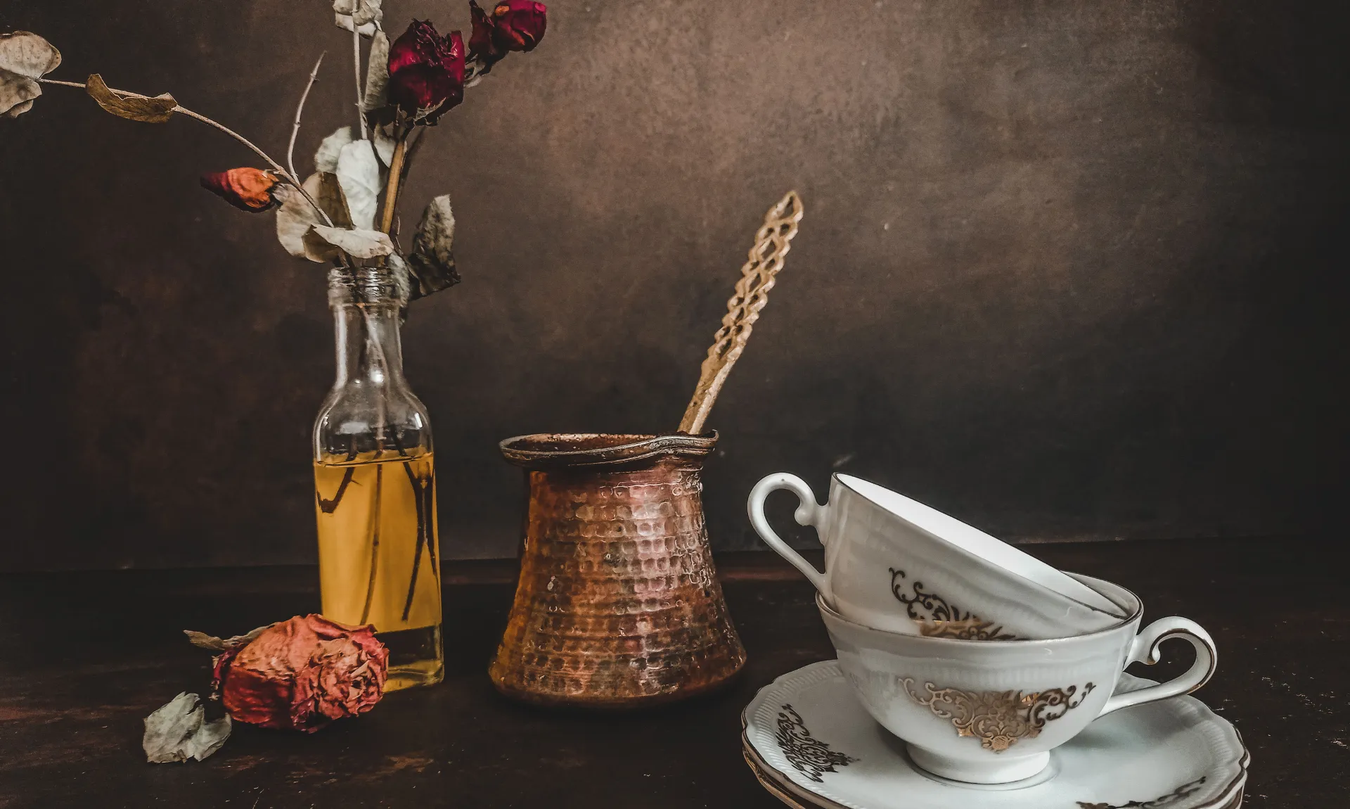 A vintage  vase, cup and saucer, with some flowers in a glass bottle to present the thrift store finds that can be used in home decor