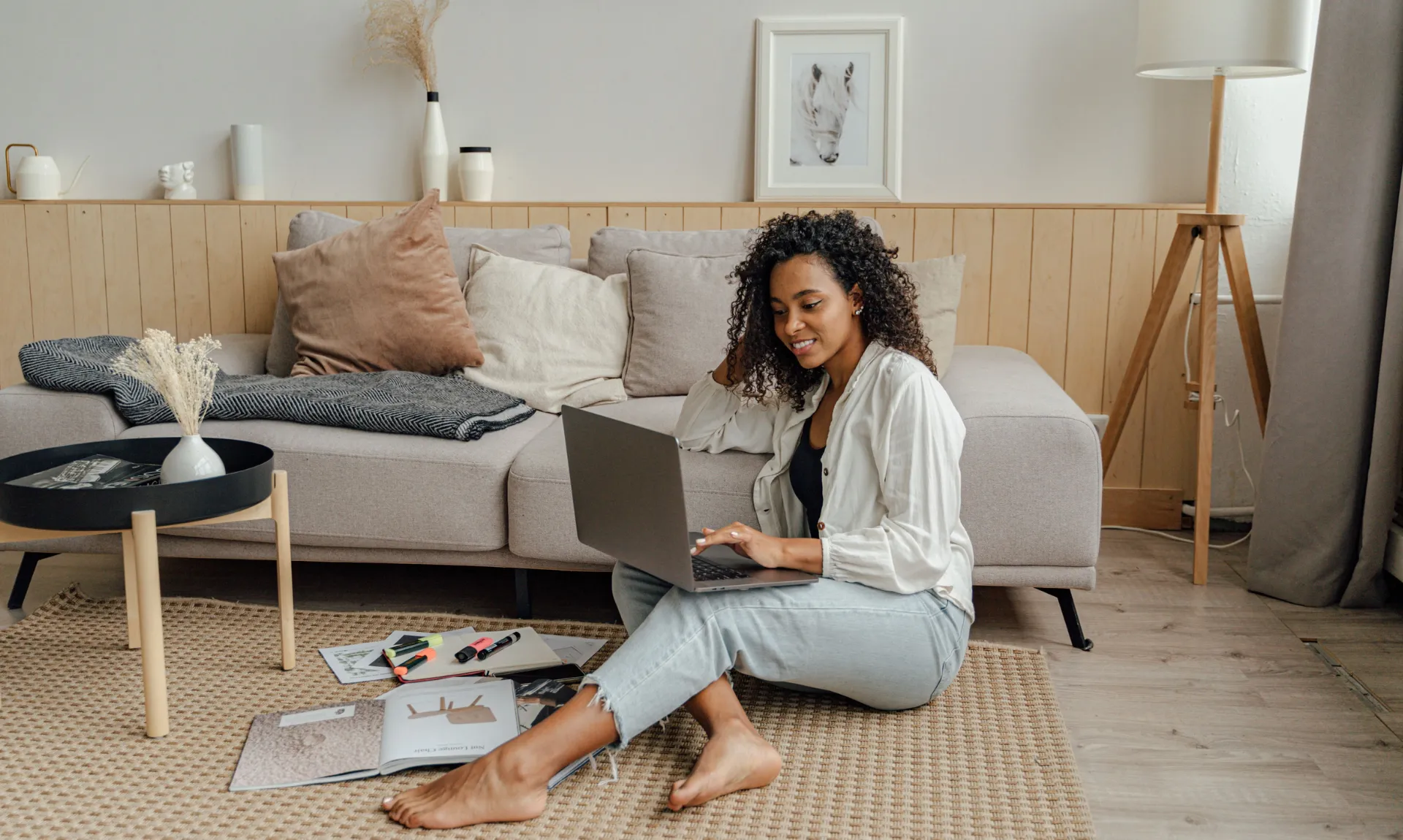 A girl sitting in her small living room with books and magazines lying around