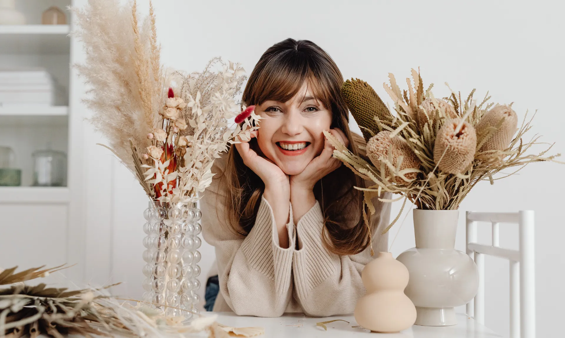 a girl similing with diy vases around her and some branches to show diy fall decor ideas